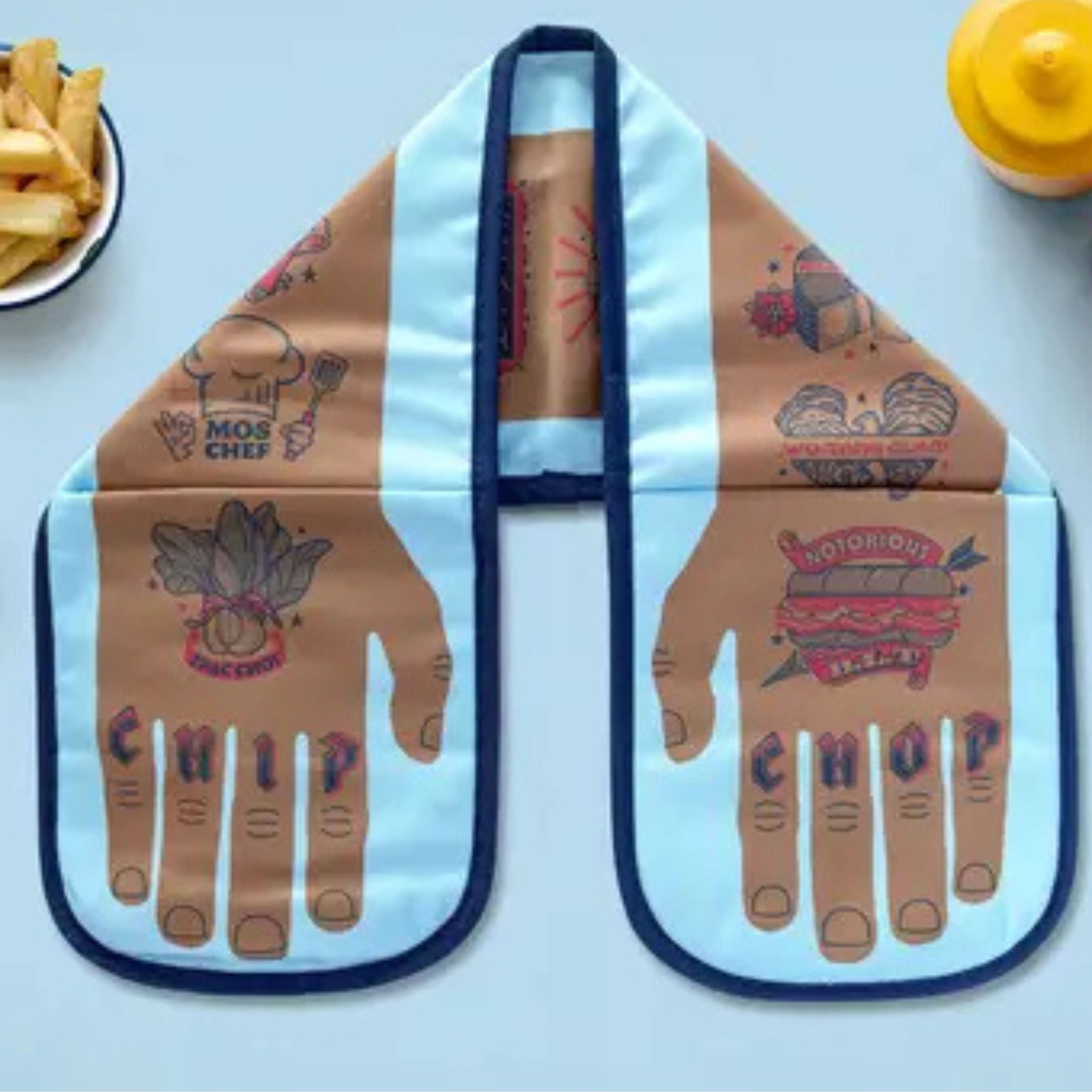 Chip Chop double oven glove with light blue panels and brown hip-hop food–pun illustrations, displayed flat on a light blue background with fries and a mustard bottle beside it.