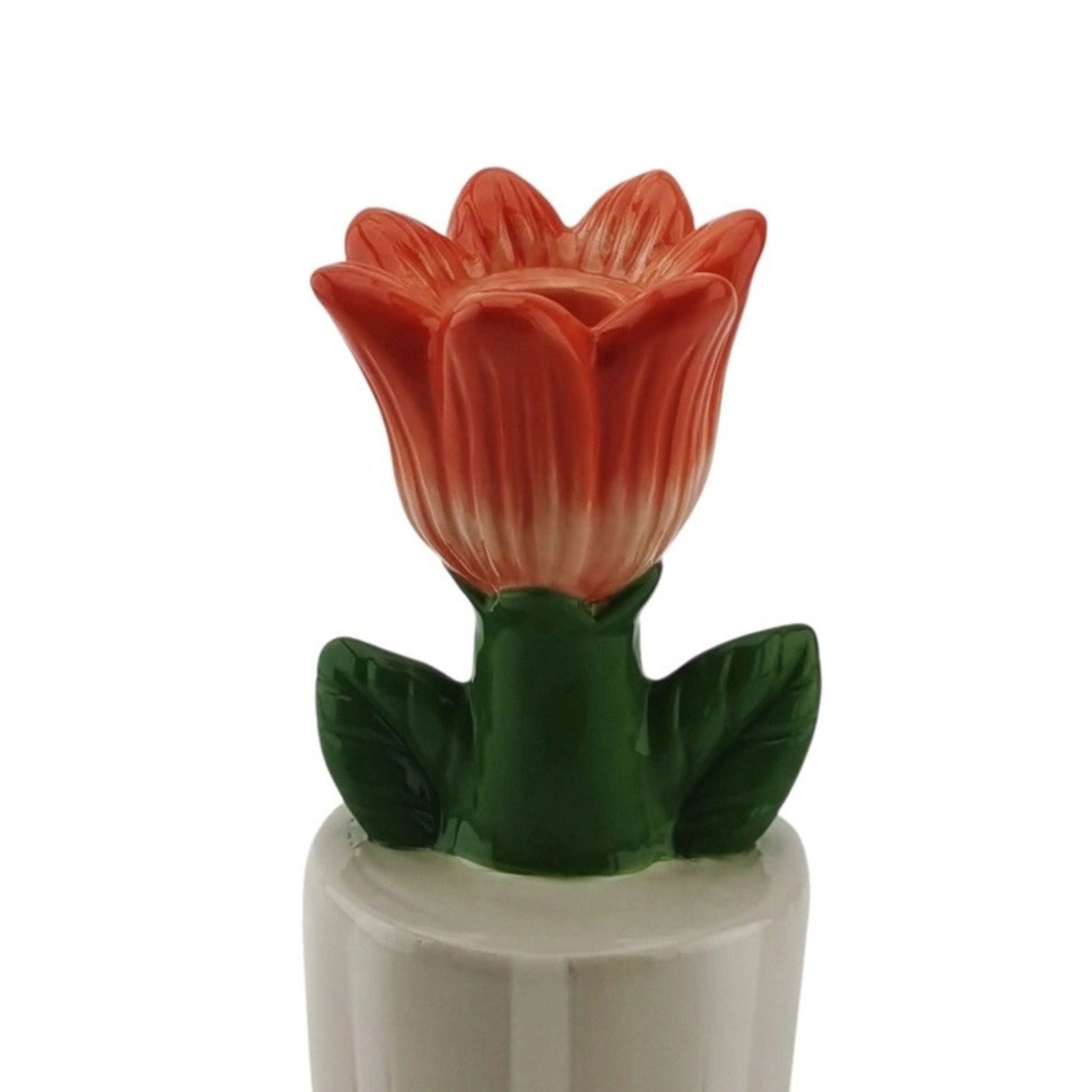 Close-up of an orange tulip-shaped stoneware candle holder with green leaves, shown on a white background.
