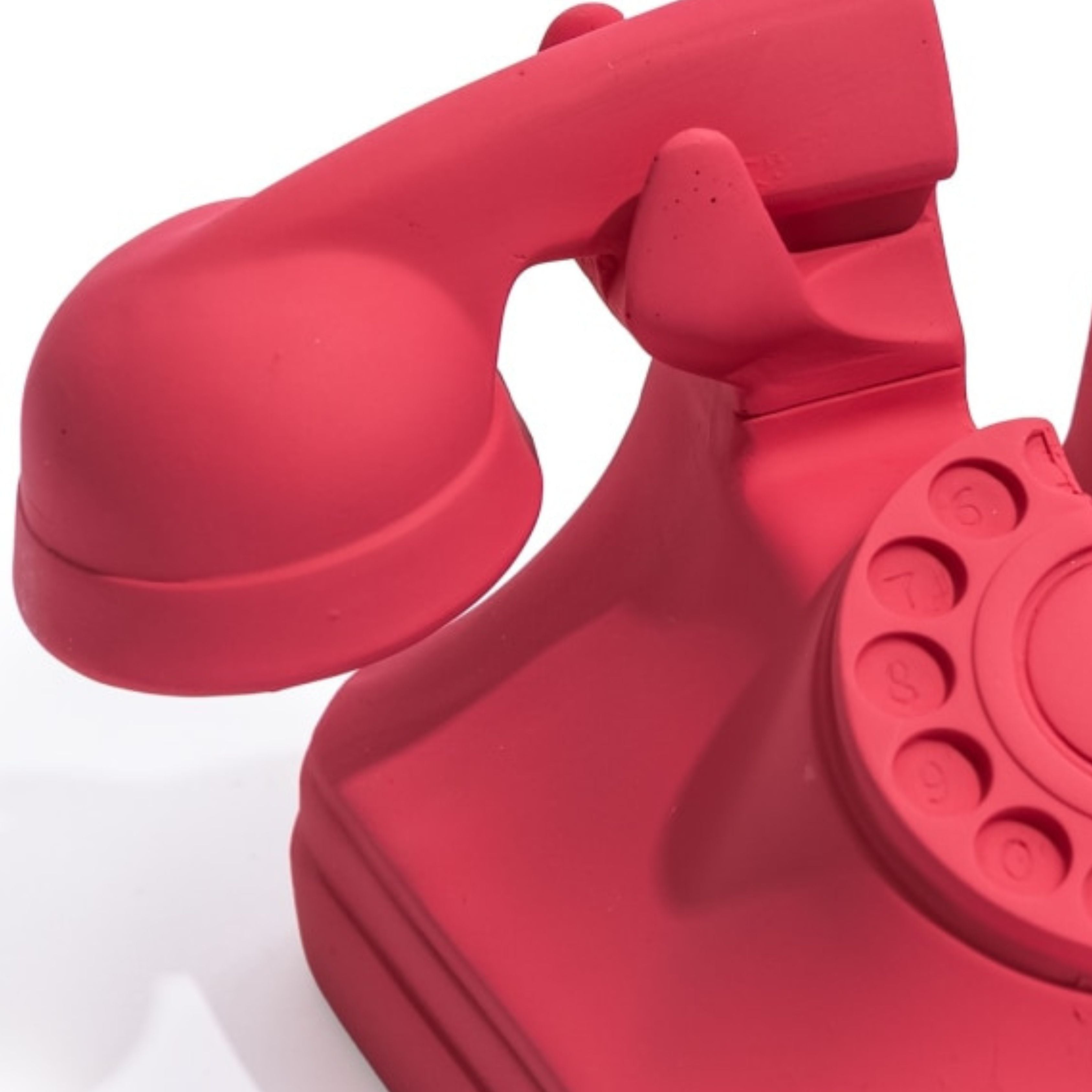 Close up of matt pink red retro rotary telephone bookend on white background