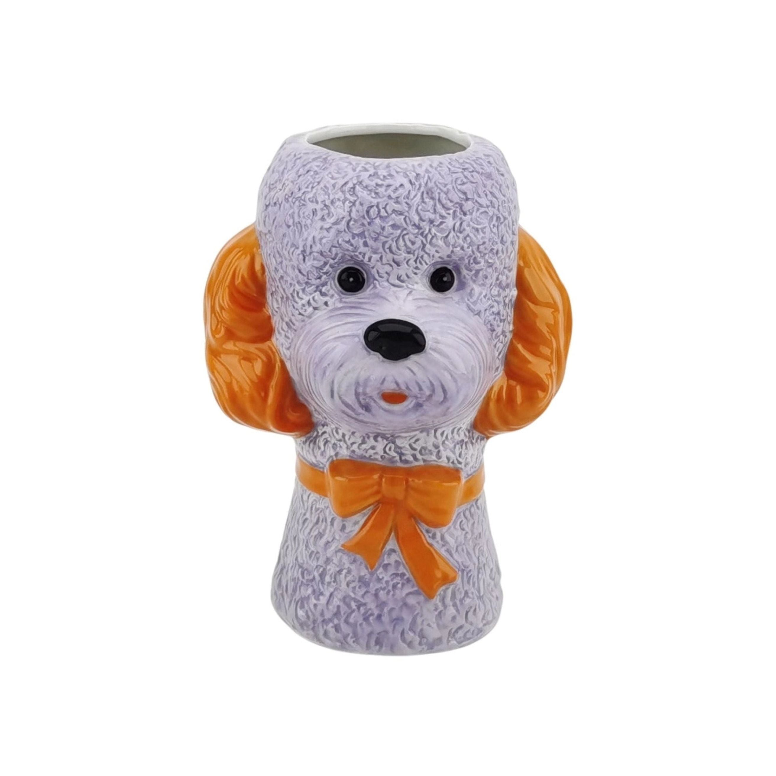 Lilac dog-shaped ceramic vase with orange ears and an orange bow on a white background.