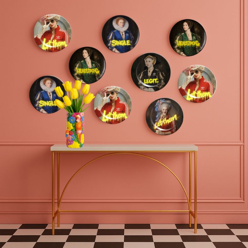 Royal Rebels decorative plates by Sammy Bird styled on a pink wall above a console table with flowers, maximalist gallery wall decor
