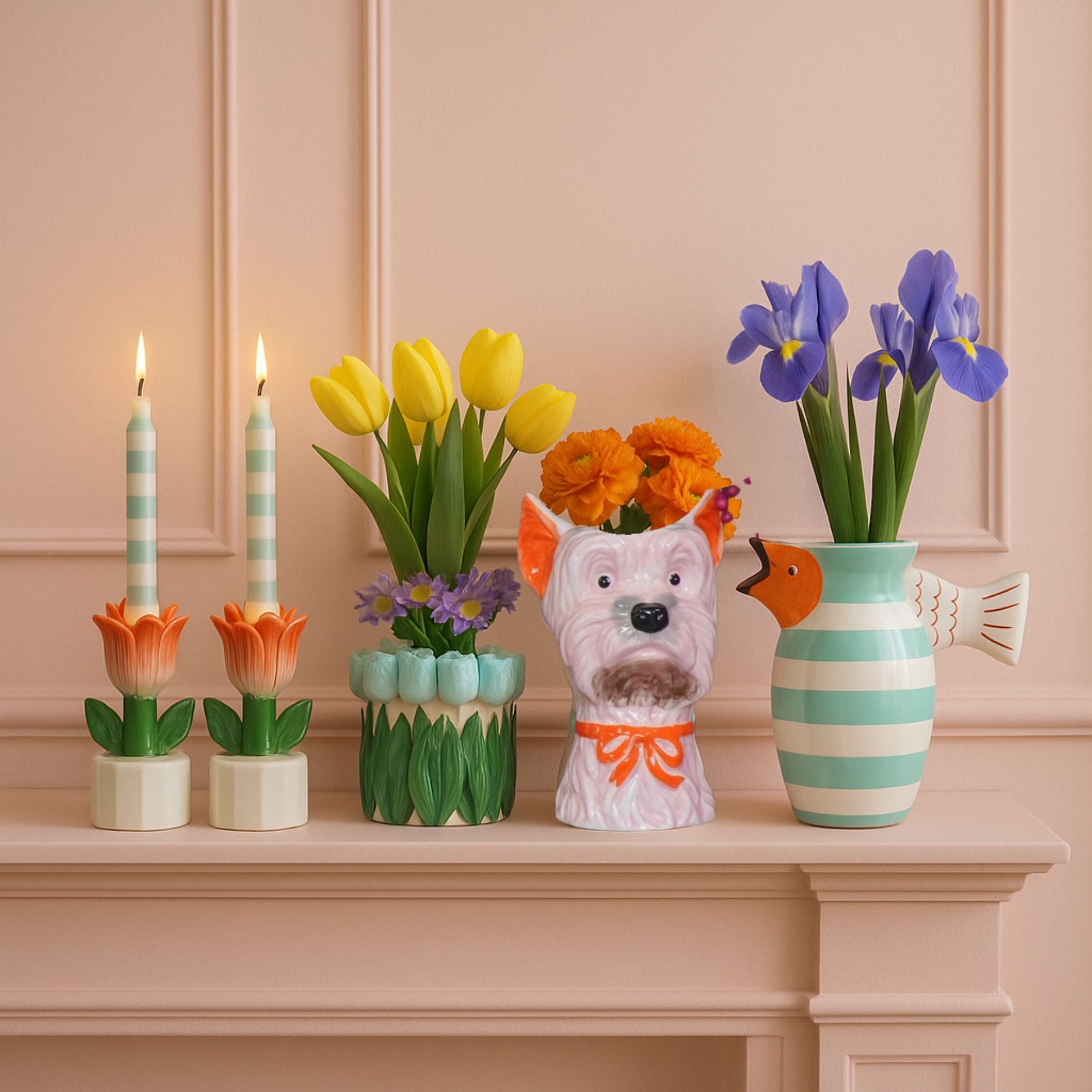 decorative mantel display with colourful candles, flower vases, and a pink and orange dog-shaped ceramic vase