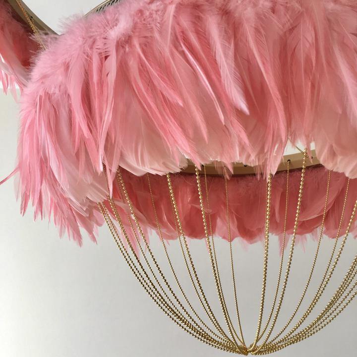 Close-up of flamingo pink Bertie two-tier feather light shade showing soft feathers and gold wire frame against a white background.
