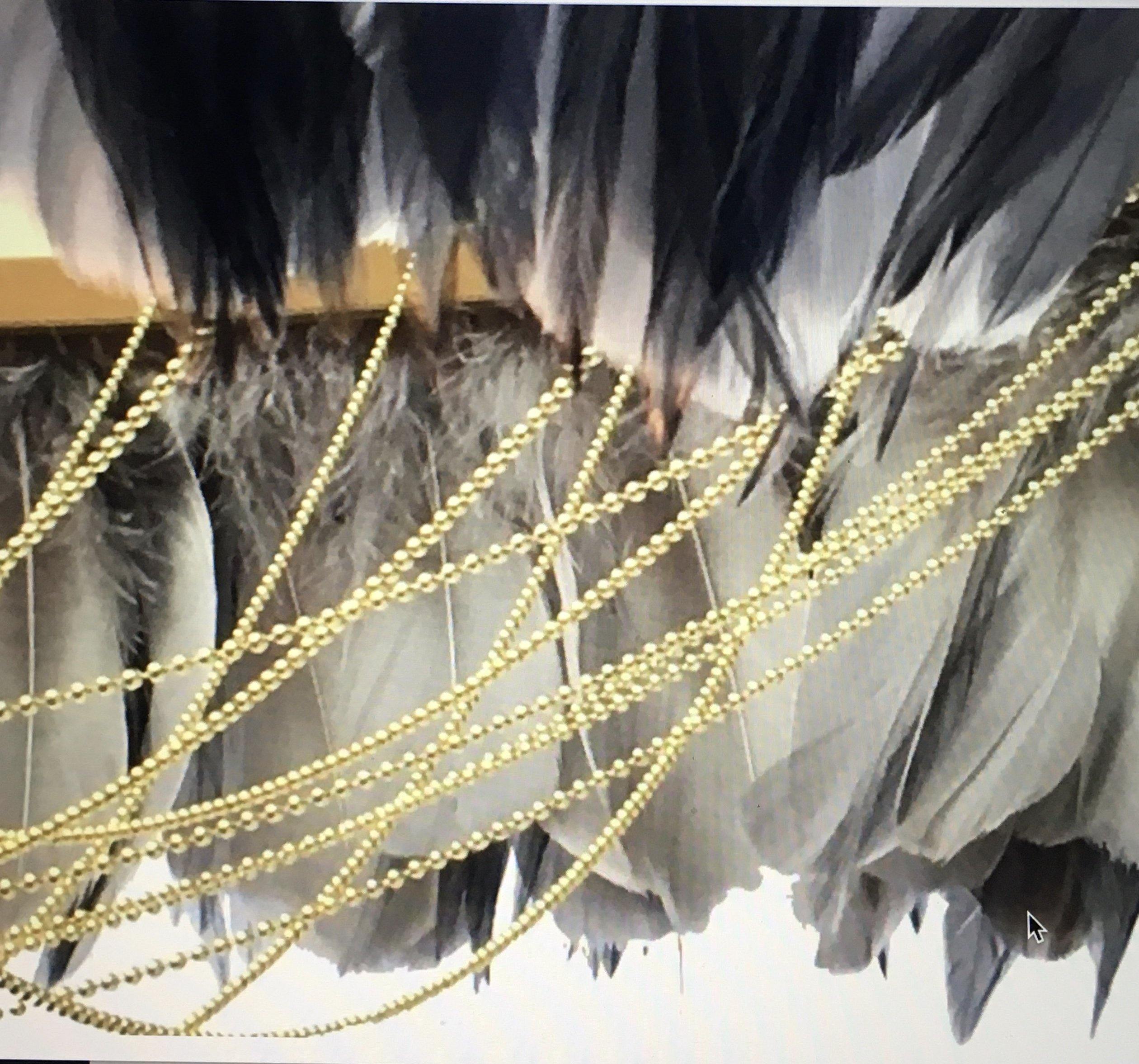 Close-up of the Gloria two-tone grey feather light shade showing layers of soft grey feathers with draped brass ball-chain detail.