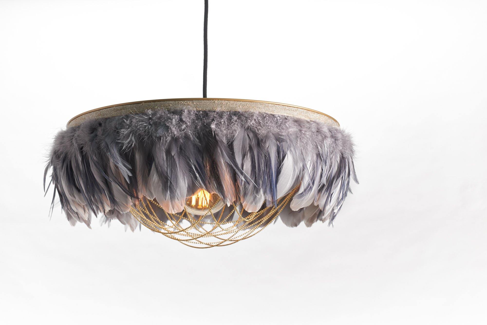 Close-up of the Gloria two-tone grey feather light shade showing soft grey feathers, brass ball-chain trim and a hanging crystal detail.