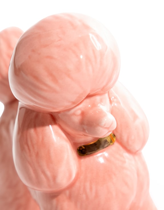 Close-up of pink ceramic poodle candle holder with gold collar detail on white background