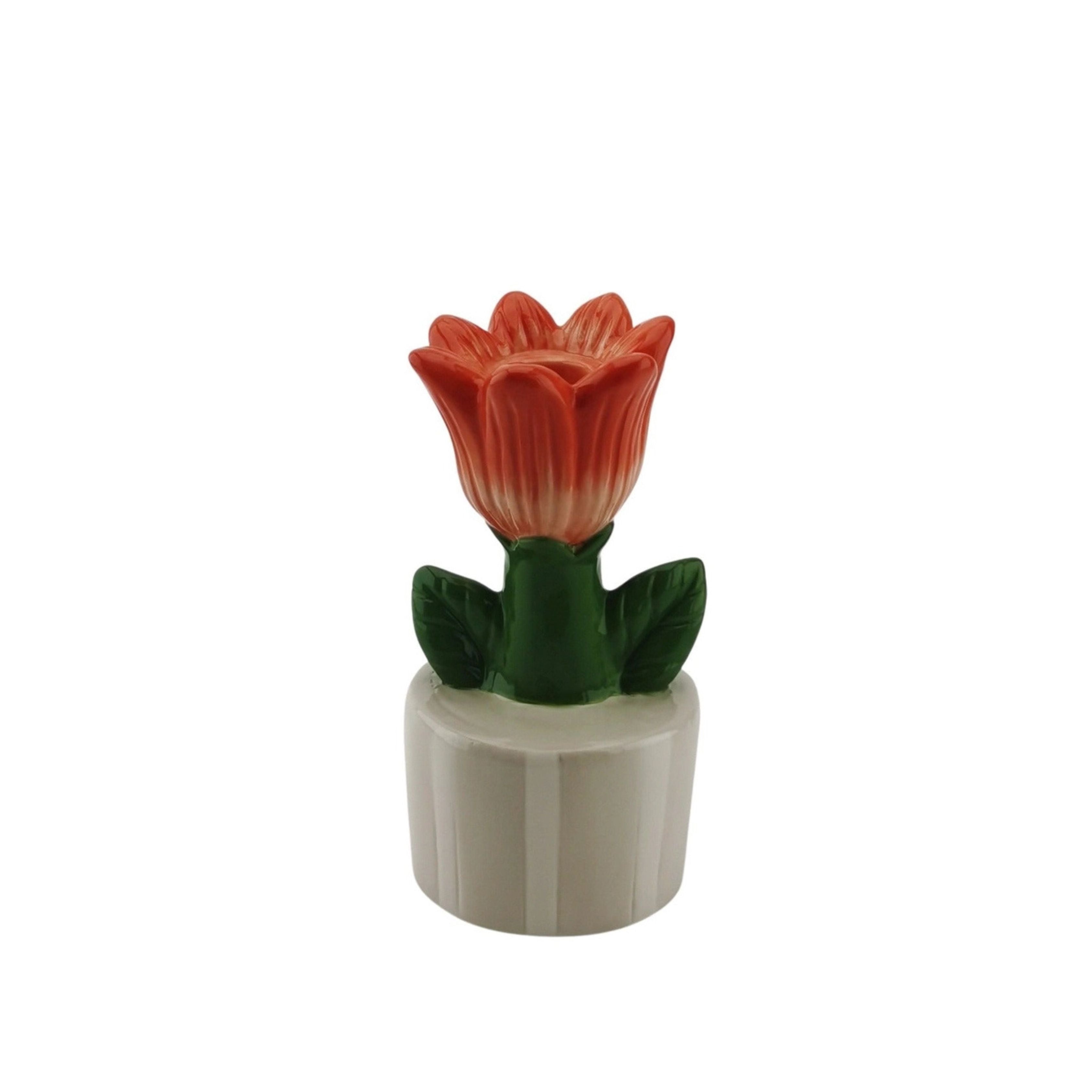 Orange tulip-shaped stoneware candle holder with green leaves, displayed on a white background.