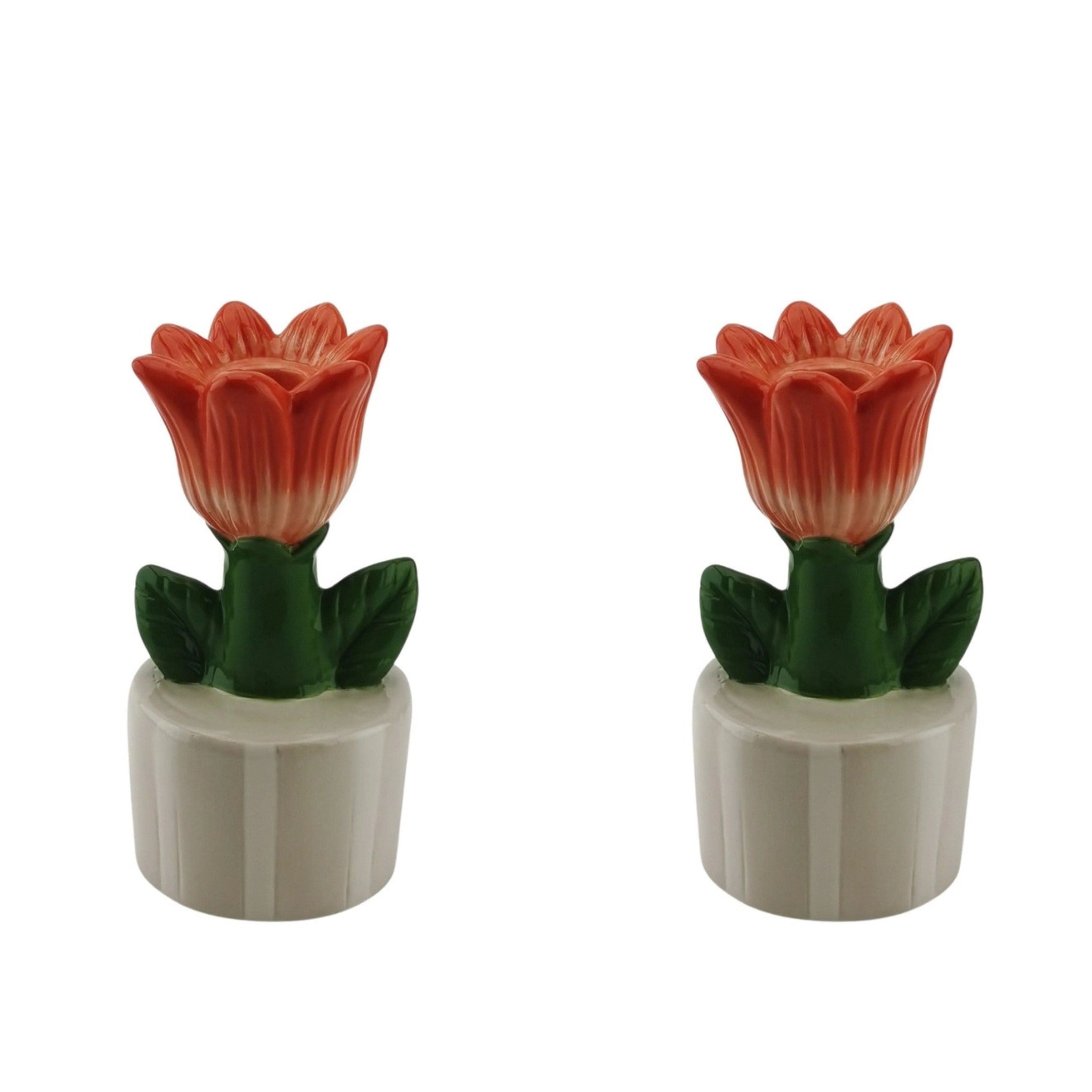Two orange tulip-shaped stoneware candle holders with green leaves, displayed on a white background.