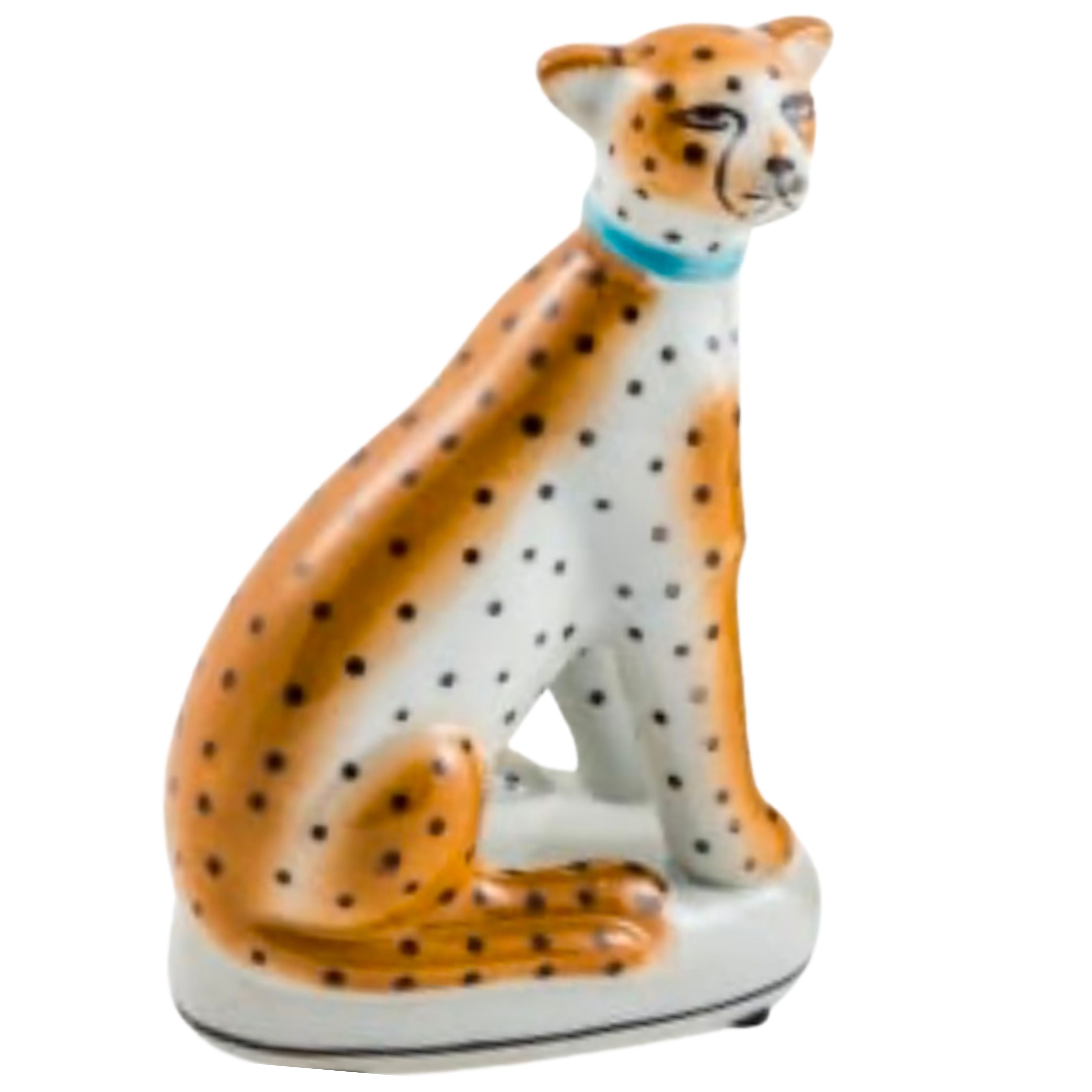 ceramic sitting leopard figure with orange and black spots decorative animal ornament on white background